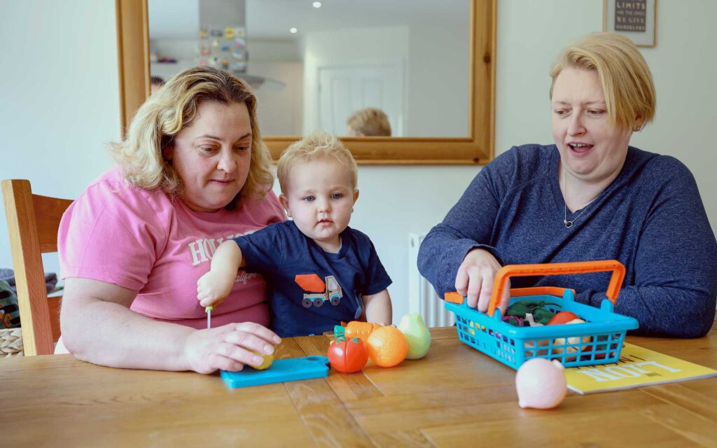 Young adopted boy sat at a table with his adopted parents